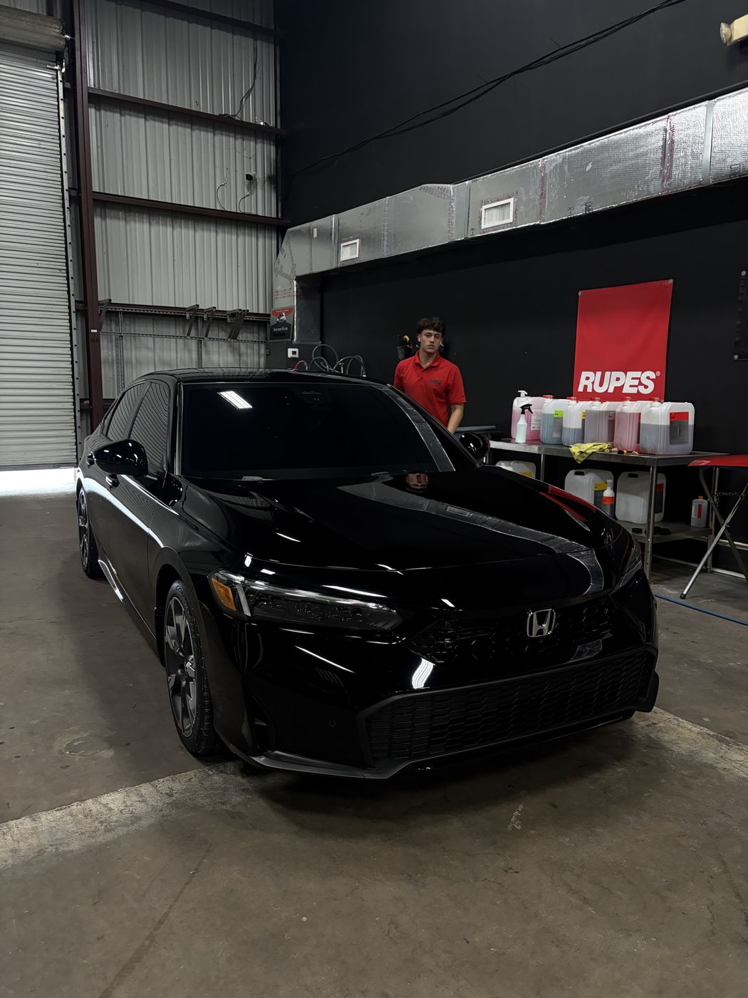 APES team member with a ceramic coated black Honda Civic in the shop